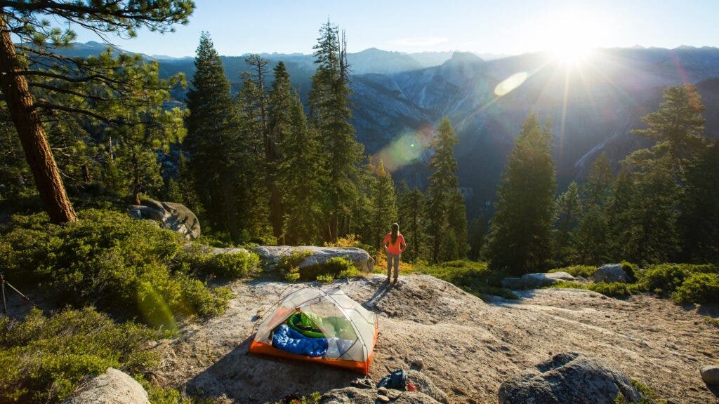 A camper on a bluff at dusk looking out at Yosemite Valley