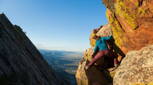 hiker scrambling up rocks near a ledge