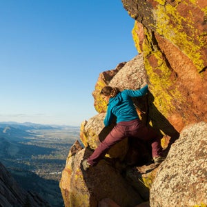 hiker scrambling up rocks near a ledge