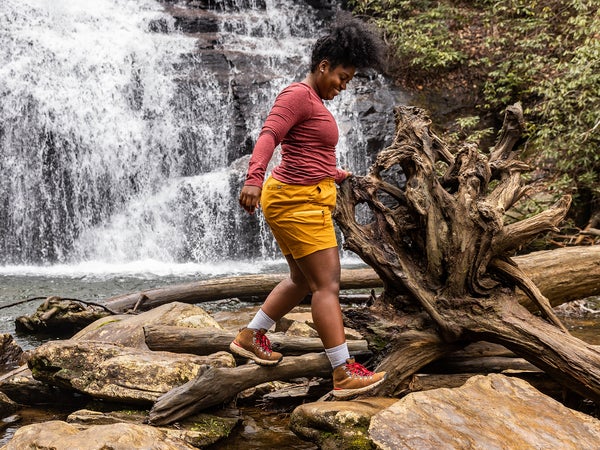 A hiker walks in front of a waterfall.