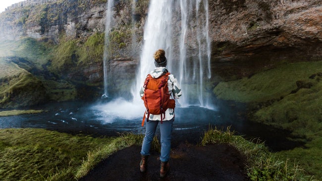 woman hiking in Iceland near a beautiful waterfall in the southern region.
