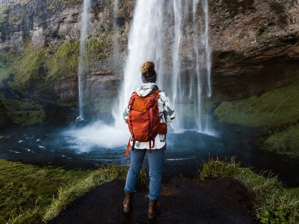 woman hiking in Iceland near a beautiful waterfall in the southern region.