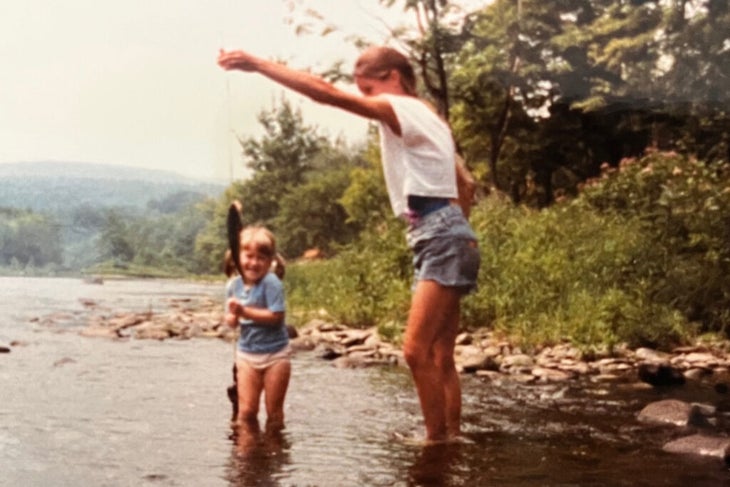 The author, as a child, fishing in a river with her mom, who is by her side
