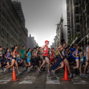 A group of runners cross a road with gray in the background