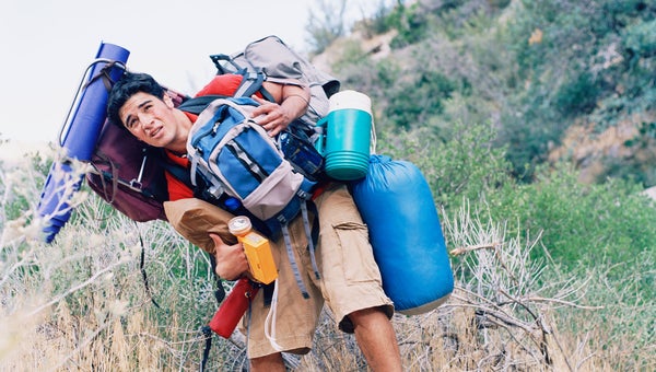 man trying to carry too much camping gear