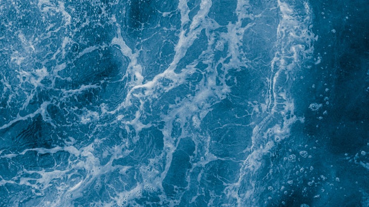 Dark blue sea surface with waves, splash and bubbles