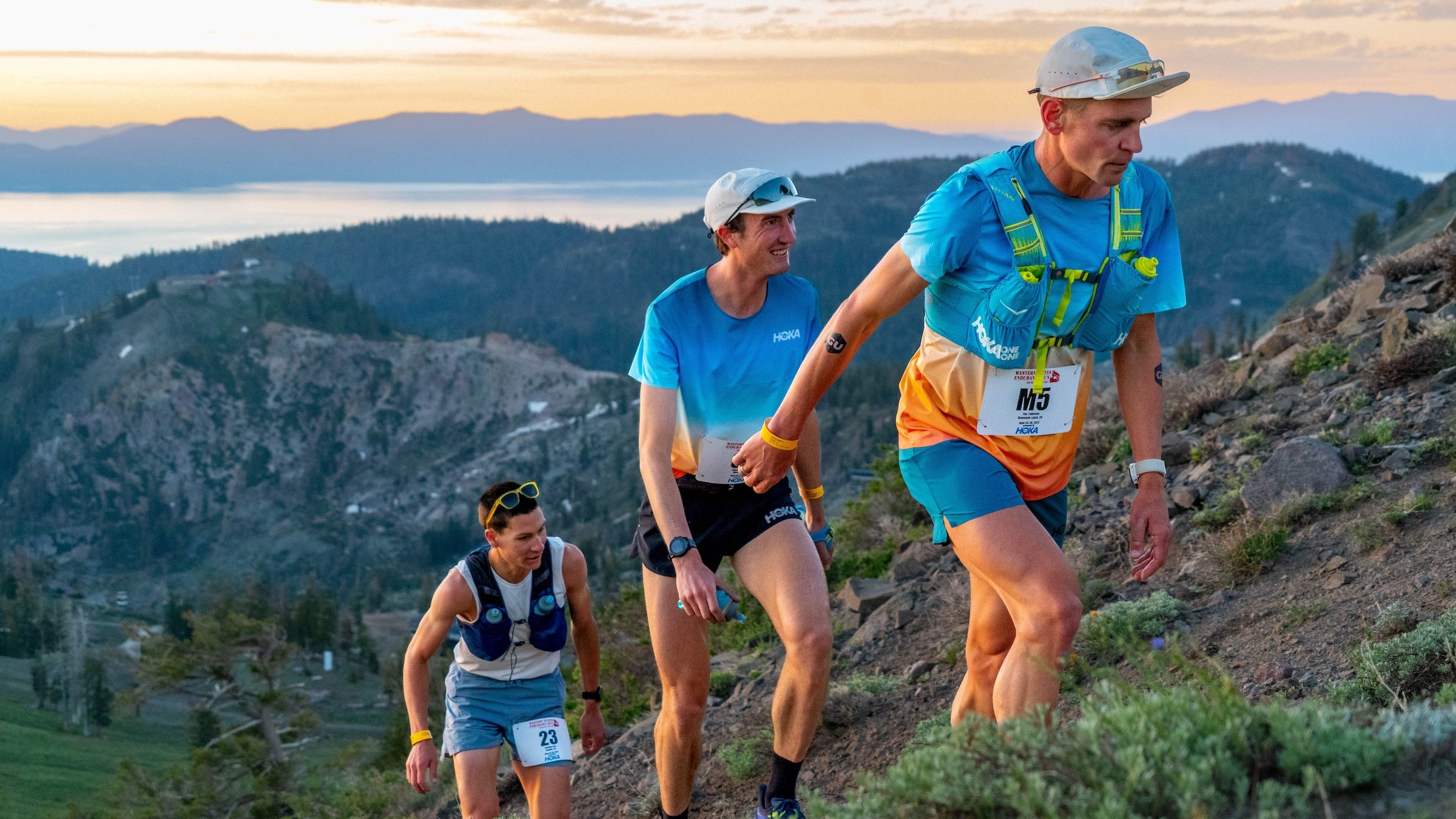 Three men hike up mountain at sunrise in Tahoe with multicolored shirts