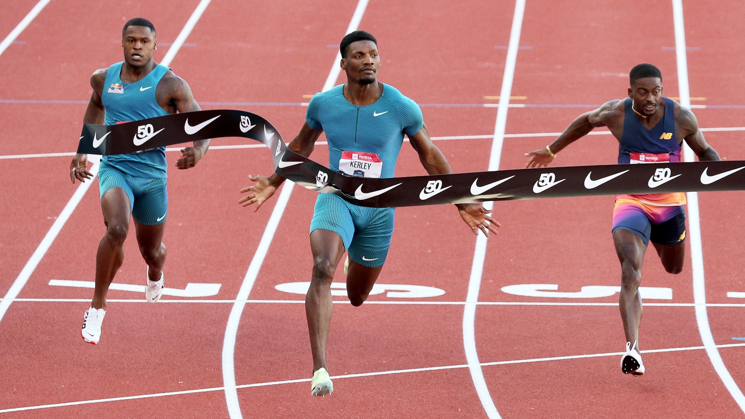Three men hit the finish line at the same time on a red track