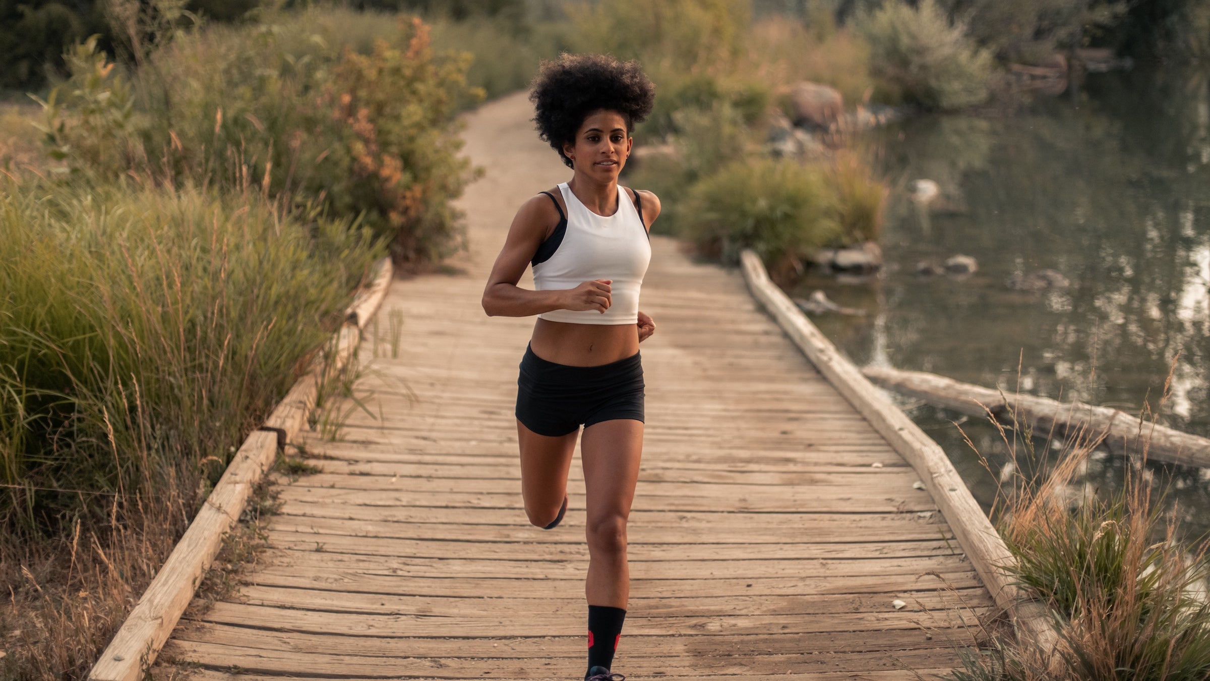 Woman in a white top running on a bridge in a field