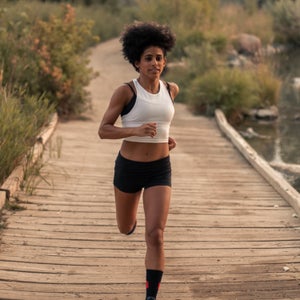 Woman in a white top running on a bridge in a field