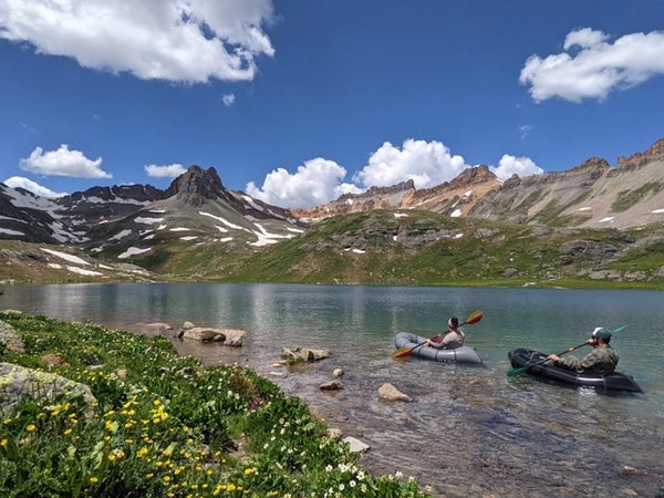 Two people in boats are floating on a high alpine lake