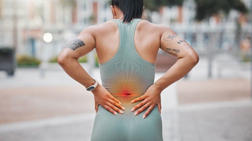 Closeup shot of a young african american woman suffering with back pain while working out in the city. Superimposed cgi highlighting an injury where a female athlete is struggling with lower back ache