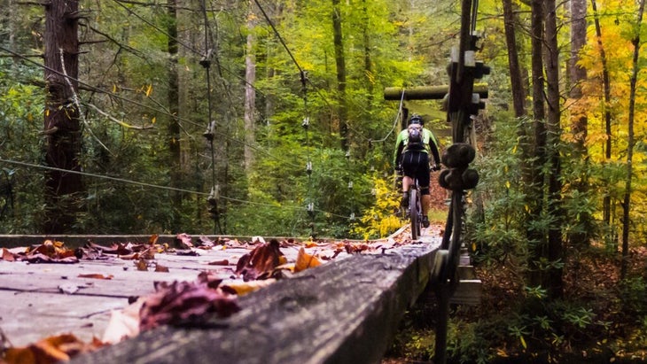 A cyclist heads over a wooden bridge in the Pisgah National Forest