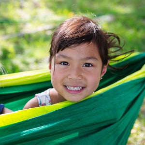 Smiling sisters sitting in green hammock at camp ground