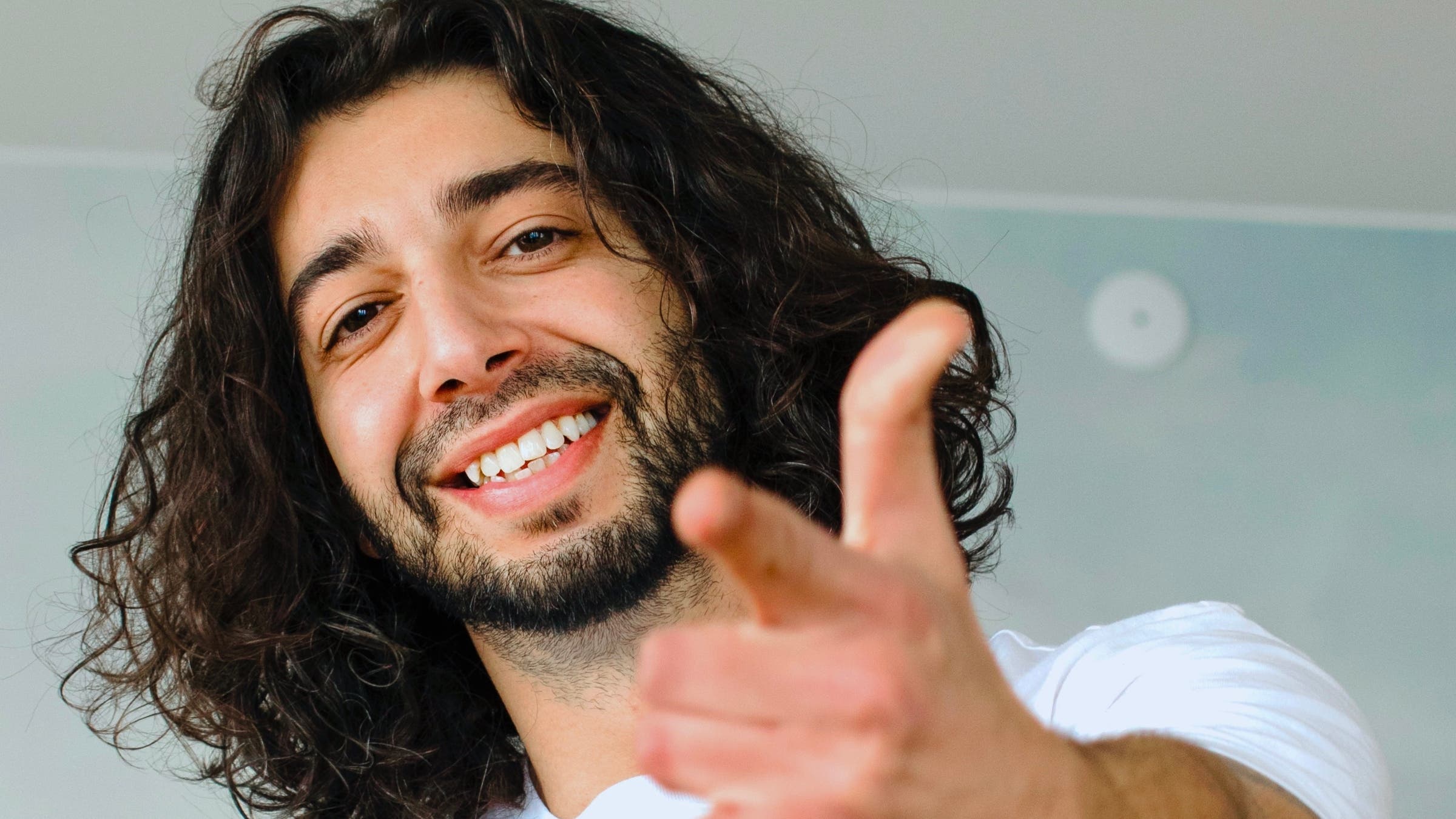 Man with long black hair pointing at camera, Armen Adamjan, king of sustainability hacks
