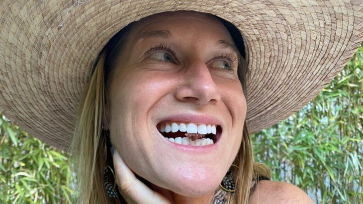 The author wearing a sombrero and showing off the grasshopper in between her teeth