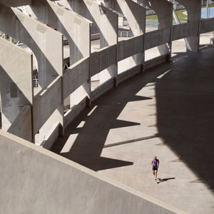 Long shot of a male athlete as he runs through a concrete stadium