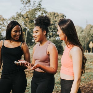 Three women gossip while walking in the park
