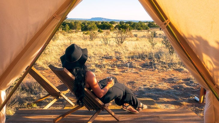 A woman relaxes in front of her tent while looking out at the Galileo Basin Preserve.