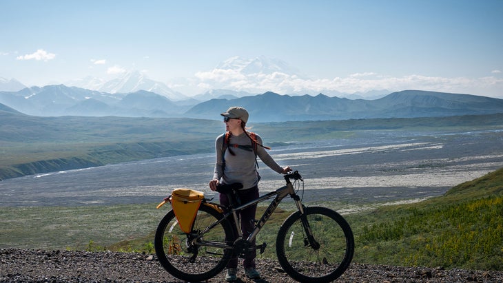 a woman with a bike and a beautiful landscape