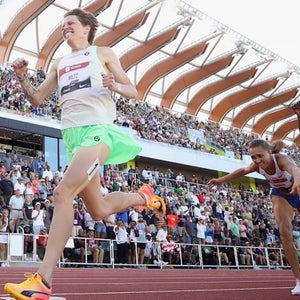 Three athletes cross a finish line on a red track