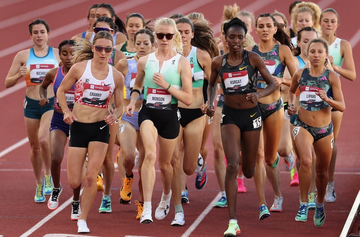 A dozen women cluster on a track and are running together