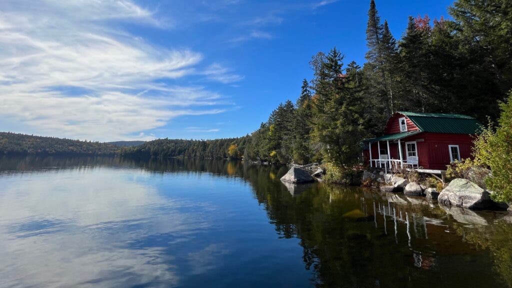 A camp building set right on the shore of a very still Fourth Debsconeag Lake