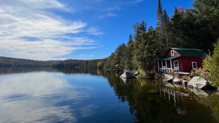 A camp building set right on the shore of a very still Fourth Debsconeag Lake