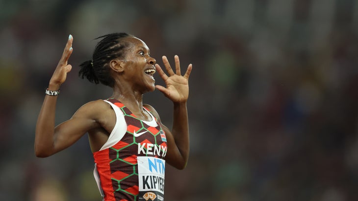 A track star celebrates in a red singlet after winning a race