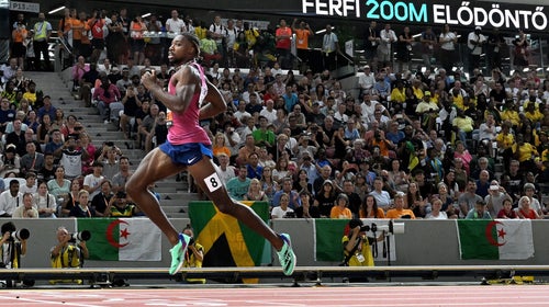A sprinter in green shoes and a red shirt finishes in first place