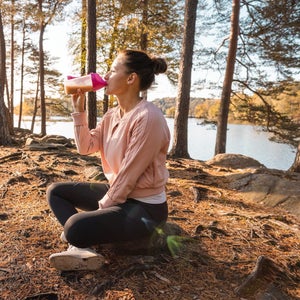 Woman drinking a protein shake after outdoor workout