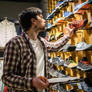 A running staff looks at a shoe on the rack
