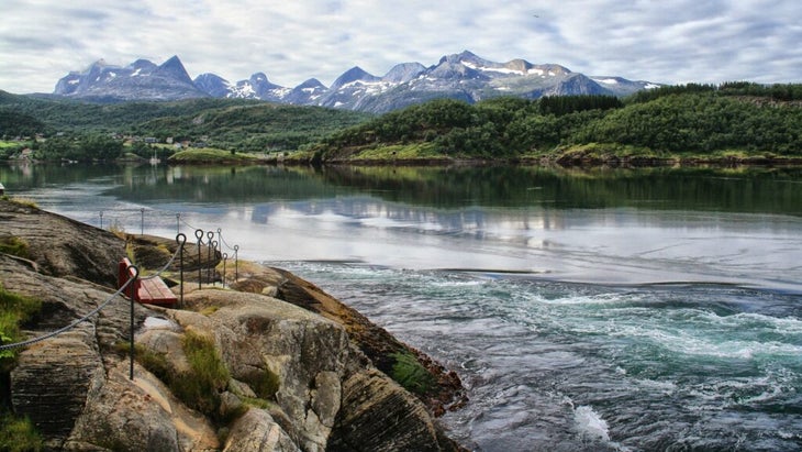 A view of the strong current of Saltstraumen, the most powerful tidal stream in the world, with a bench in the foreground and mountains in the background