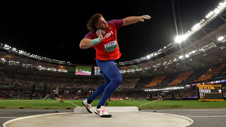 a man wearing read is about to let go of a shot put
