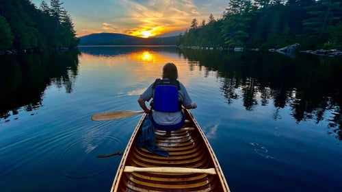 A cancer paddles toward the sunset on Maine's Fourth Debsconeag Lake