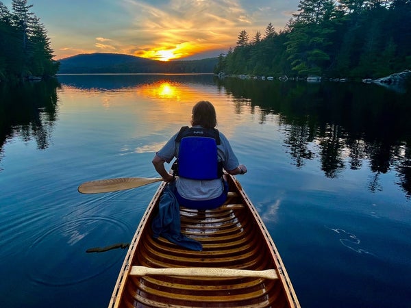 A cancer paddles toward the sunset on Maine's Fourth Debsconeag Lake