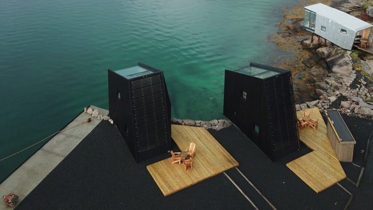 The two new solar-powered towers (with black siding) and a sea cabin (with white siding) look out on turquoise waters.