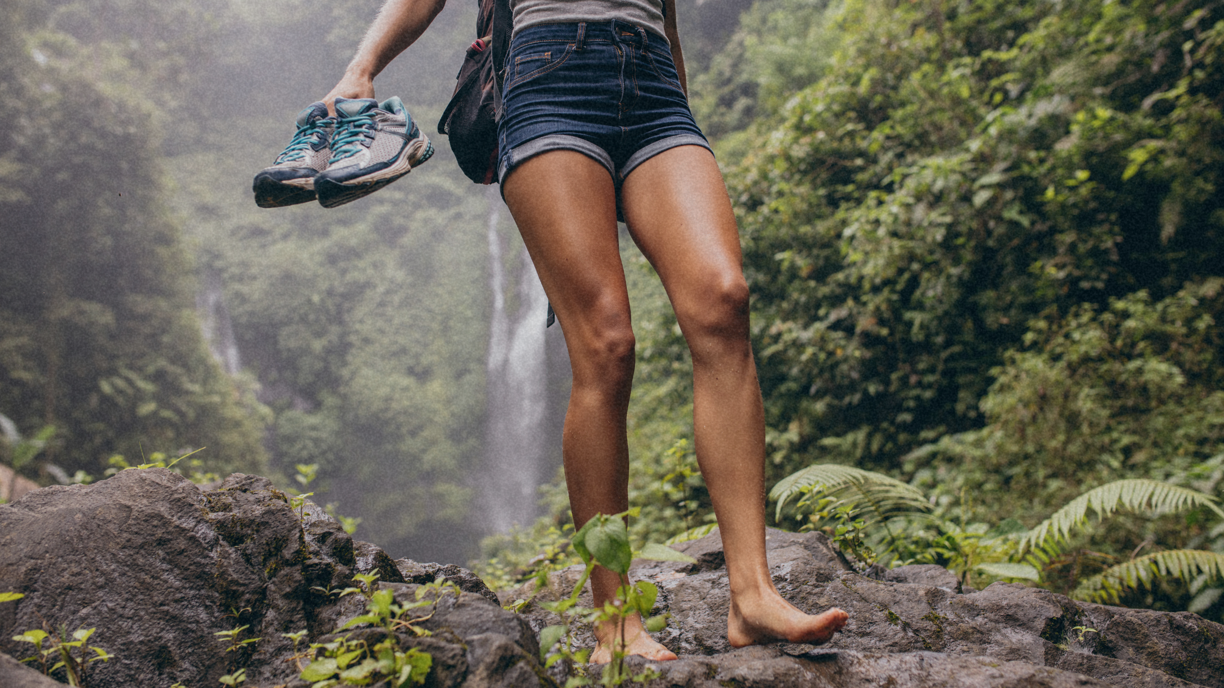 woman takes off her sneakers and walks barefoot in the forest