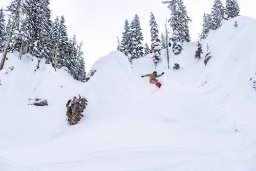 Man snowboarding under steep terrain