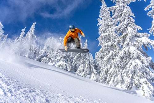 Man doing an air on a snowboard into powder