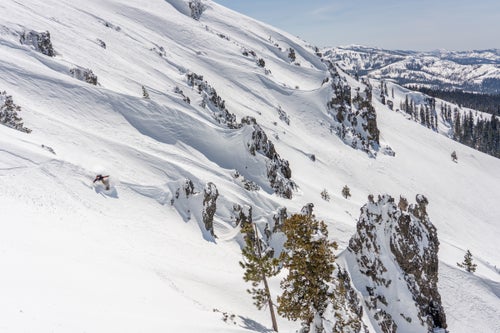 Man snowboarding with rocks in the background