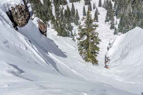 Man snowboarding down a tight chute
