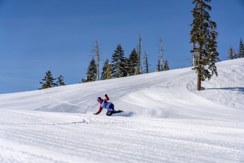 Woman carving a groomer on a snowboard