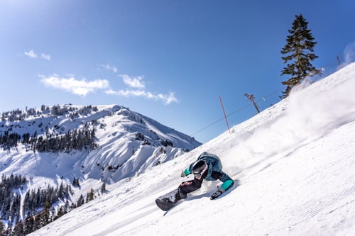 Man snowboarding with steep terrain in the background