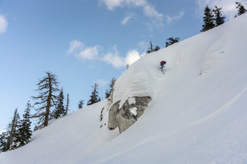 Man snowboarding above rocks
