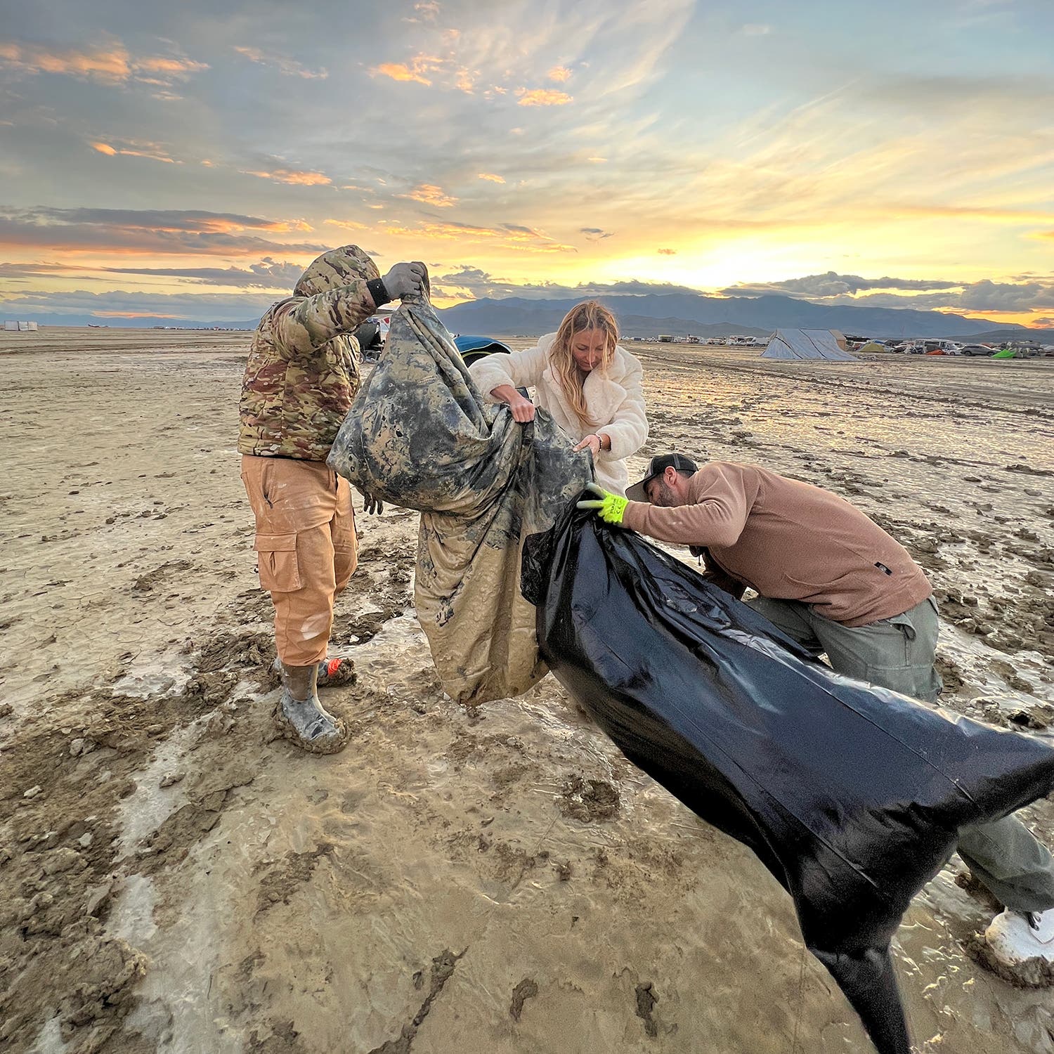 Friends help me load the mud-laden flood of my tent into a contractor bag.