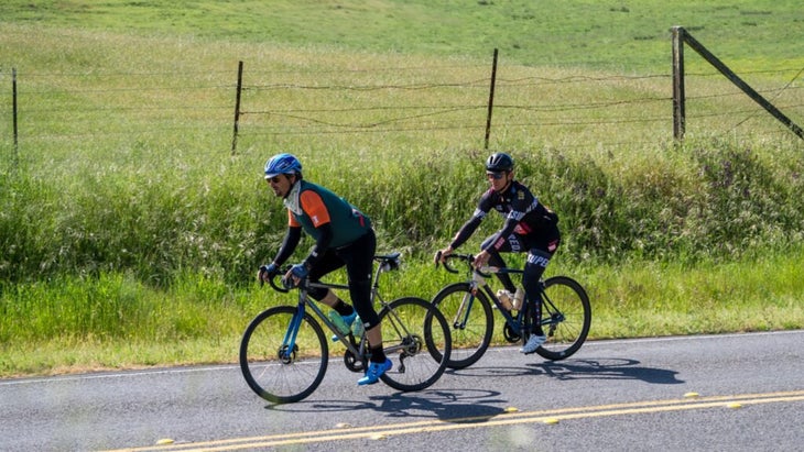 Chef Chris Cosentino and a friend riding the roads of West Marin, with green fields and hills next to them