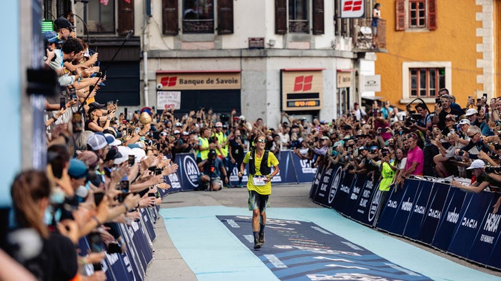 a woman in a yellow shirt finishes the race to a large crowd