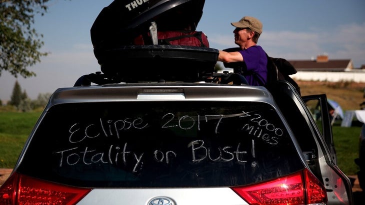 The rear window of a car reads "Eclipse 2017 Totality or Bust! +2000 Miles"