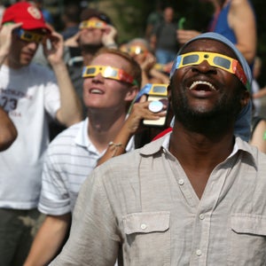 Two men wearing safety glasses look up at the sky in awe during the 2017 total solar eclipse.